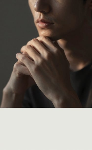 Fine art portrait of a subject in a thoughtful pose, soft light illuminating only the hands and half the face, deep chiaroscuro style, tones of #4C4A48 and #F5F2EF, warm and personal atmosphere.