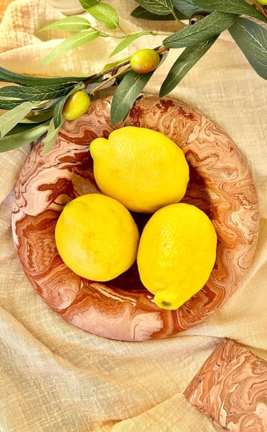 3 citrons jaunes posés sur une assiette en marbre terracotta