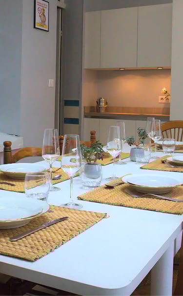 Salle à manger avec grande table dressée et cuisine équipée pour équipes en mission.