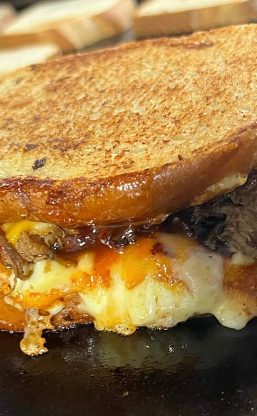 Grilled brisket and cheese sandwich from Slap Yo Self BBQ, featuring slow-smoked brisket, melted cheese, and BBQ sauce presse
