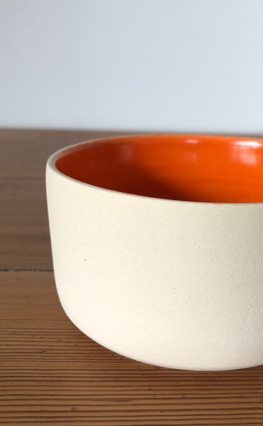 un bol blanc émaillé en orange à l'intérieur