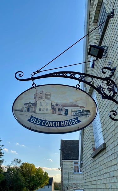 A classic sign indicating the old coach house, affixed to a brick structure, reflecting its historical significance. 