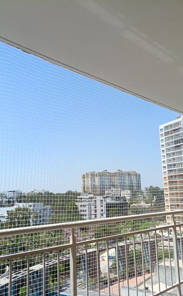 Wide shot of a multi-story apartment building in Whitefield with safety nets installed on balconies.