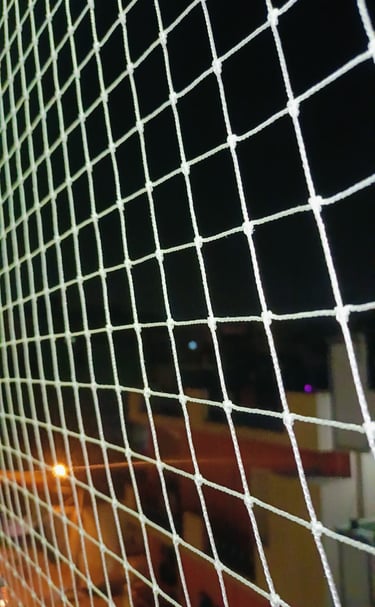 Evening view of a balcony net gently illuminated by warm indoor lights, ensuring safety and peace.
