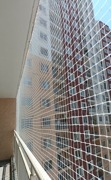 Evening view of a balcony with pigeon netting, city lights twinkling in the background.