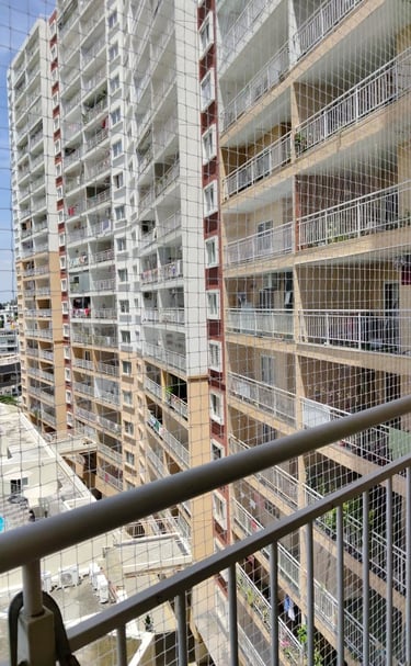 Technician carefully fitting a safety net frame on a residential balcony.