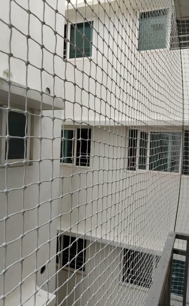 Close-up of a sturdy anti-pigeon safety net tightly secured on a balcony railing.