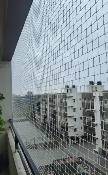 Close-up of a freshly installed black pigeon net on a modern Navi Mumbai balcony under sunlight