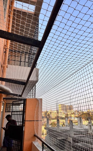 Close-up of a sturdy pigeon net tightly fitted on a balcony railing with a view of Mumbai skyline.