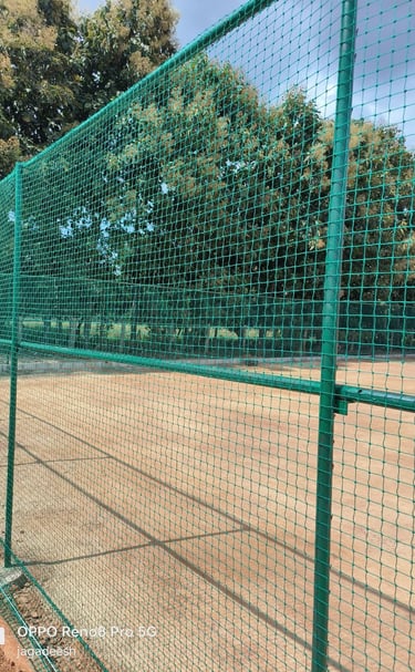Technicians securing white sports nets with precision on a terrace in Bangalore.
