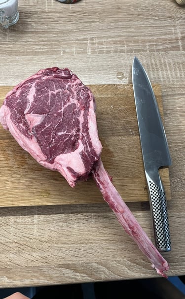 Surowy stek tomahawk i nóż na desce. Ubezpieczenia A&K Wawro to też miłość do gotowania.