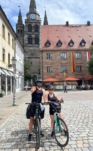 Karolina i Arek na rowerach na rynku zabytkowego miasta. Twój doradca ubezpieczeniowy w akcji.