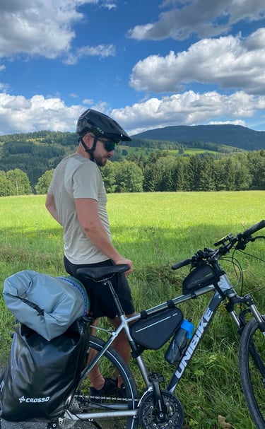 Arek z rowerem na tle zielonych łąk i gór. Ubezpieczenia A&K Wawro to też pasja do sportu.