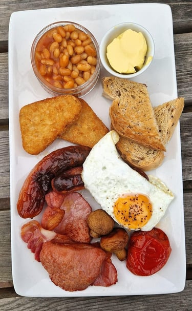 a full english breakfast with beans, butter, hash browns, toast, sausage, egg, bacon and tomato