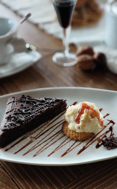 a piece of cake on a plate with a glass of wine