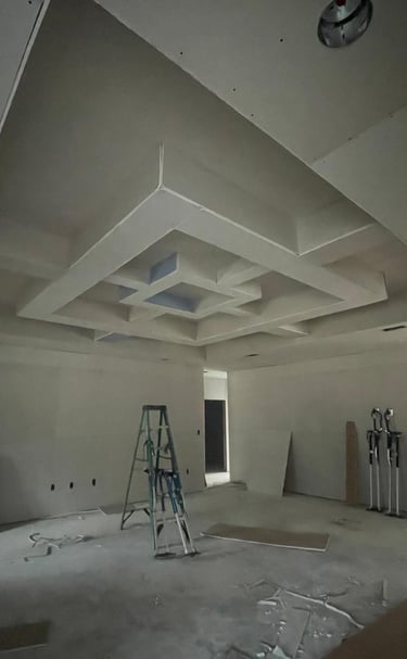 a room in the process of having drywall installed on the ceiling with work ladders