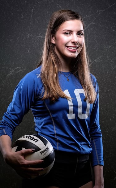 a woman in a blue shirt and shorts holding a volleyball ball