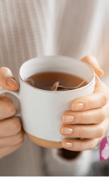 les mains d'une personne tenant une tasse de thé