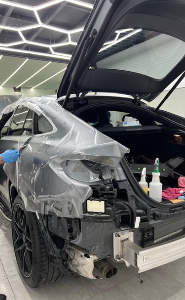 Professional installer applying a paint protection film to a luxury car for auto detailing.