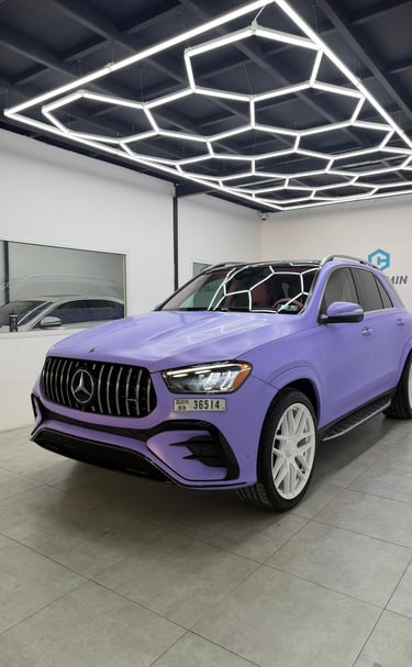 Matte purple Mercedes-Benz SUV with white wheels under hexagonal LED garage lighting.