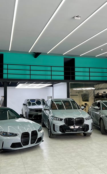 Luxury sports cars including a BMW M3 and Lamborghini Urus in a modern automotive detailing garage.