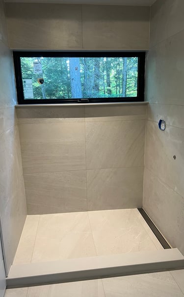Modern walk-in shower featuring large beige porcelain tiles.