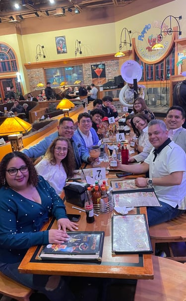 A large group of friends smiling while dining together at a lively Mexican restaurant with live music.