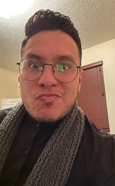 A man wearing round glasses and a grey knitted scarf making a funny face for a close-up portrait.