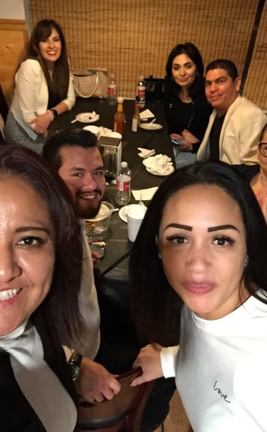 A group of happy friends taking a selfie while dining together at a restaurant table.
