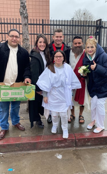 A diverse group of friends in white and red costumes pose together outdoors by a fence.