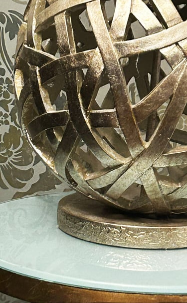 intricately designed gold metal lamp on a gold leaf and glass table