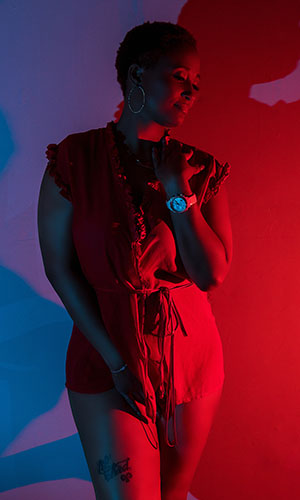a woman in a red dress standing in front of a red light boudoir shoot