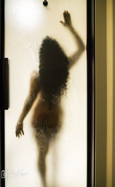 Louisiana boudoir model in a bathing suit is standing in front of a shower