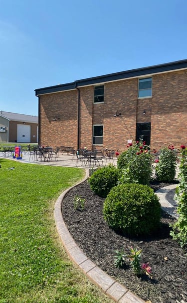 Outdoor patio at Brickyard Events with black metal tables and chairs beside a brick building under a