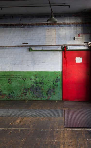 Peeling paint with an industrial original iron door with original wooden floors in the Main Room at Atlas Studios.
