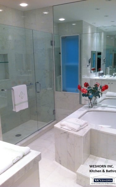 Luxury marble master bath featuring big soaking tub wall mirror, and glass walk-in shower