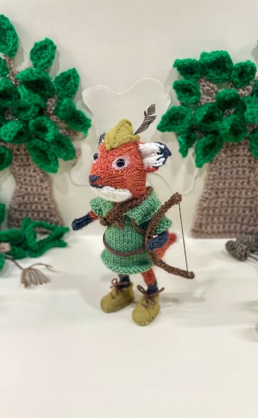 a knitted fox dressed in Disney Robin Hood outfit with a bow and arrows 