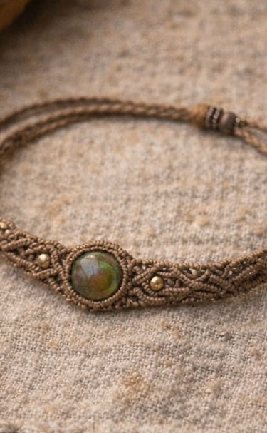 Pulsera de macramé marrón hecha a mano con una piedra preciosa verde redonda como pieza central.