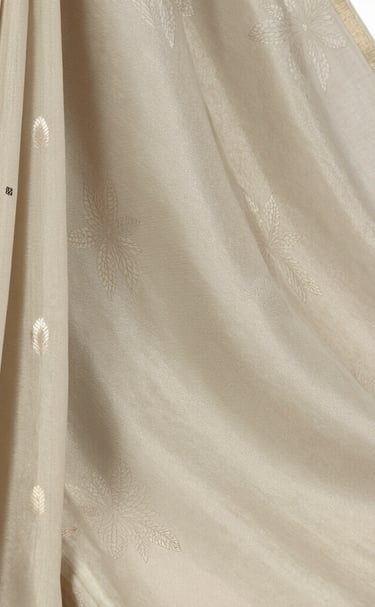 An office desk adorned with a folded katan saree and a gold-accented pen, capturing a blend of work and luxury.