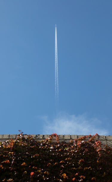 A jet flying above with a white trail behind.