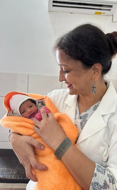 Dr. Rrenu Agraeal, Rini Hospital Dholpur-a woman in a white coat holding a baby in a hospital