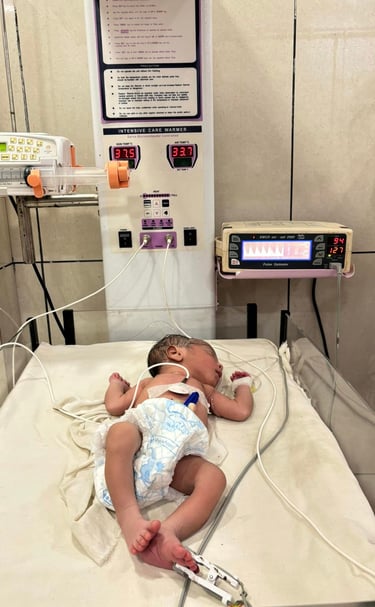 a baby in a hospital bed with a monitor and a monitor. Rini Hospital Dholpur