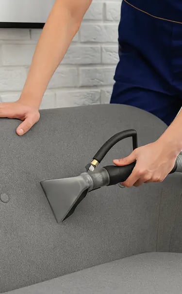 a person cleaning a couch with a vacuum