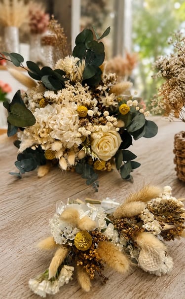 Rustic dried flower wedding bouquet and matching boutonnieres with eucalyptus and bunny tails on a wooden table.