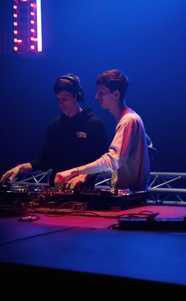 two men standing in front of a stage with a dj and a dj