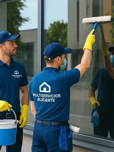 Dos trabajadores de multiservicio limpiando una cristalera de un comercio en la calle