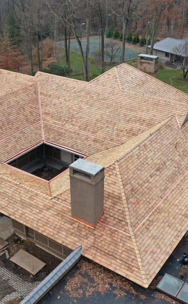 Aerial view of a luxury home featuring a new cedar shake roof with copper flashing and gutters.