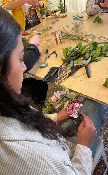 a woman is making a flower arrangement for a wreath