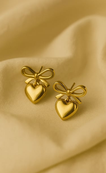 a pair of gold toned heart shaped earrings with a bow