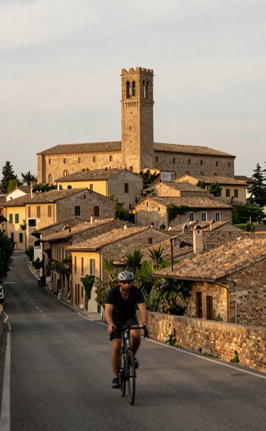Historic village streets framed by colorful houses and cyclists passing through.